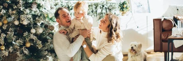 couple with child sitting in front of Christmas tree